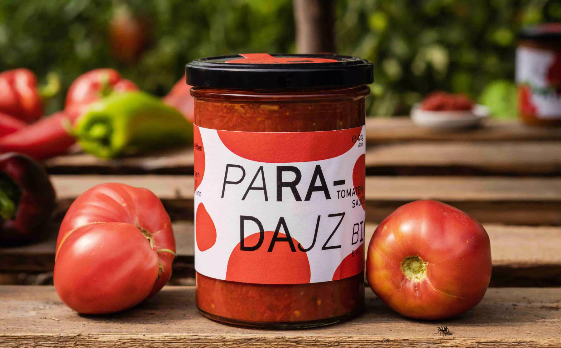 Ein Glas Bio-Paradajz mit Tomaten am Brett