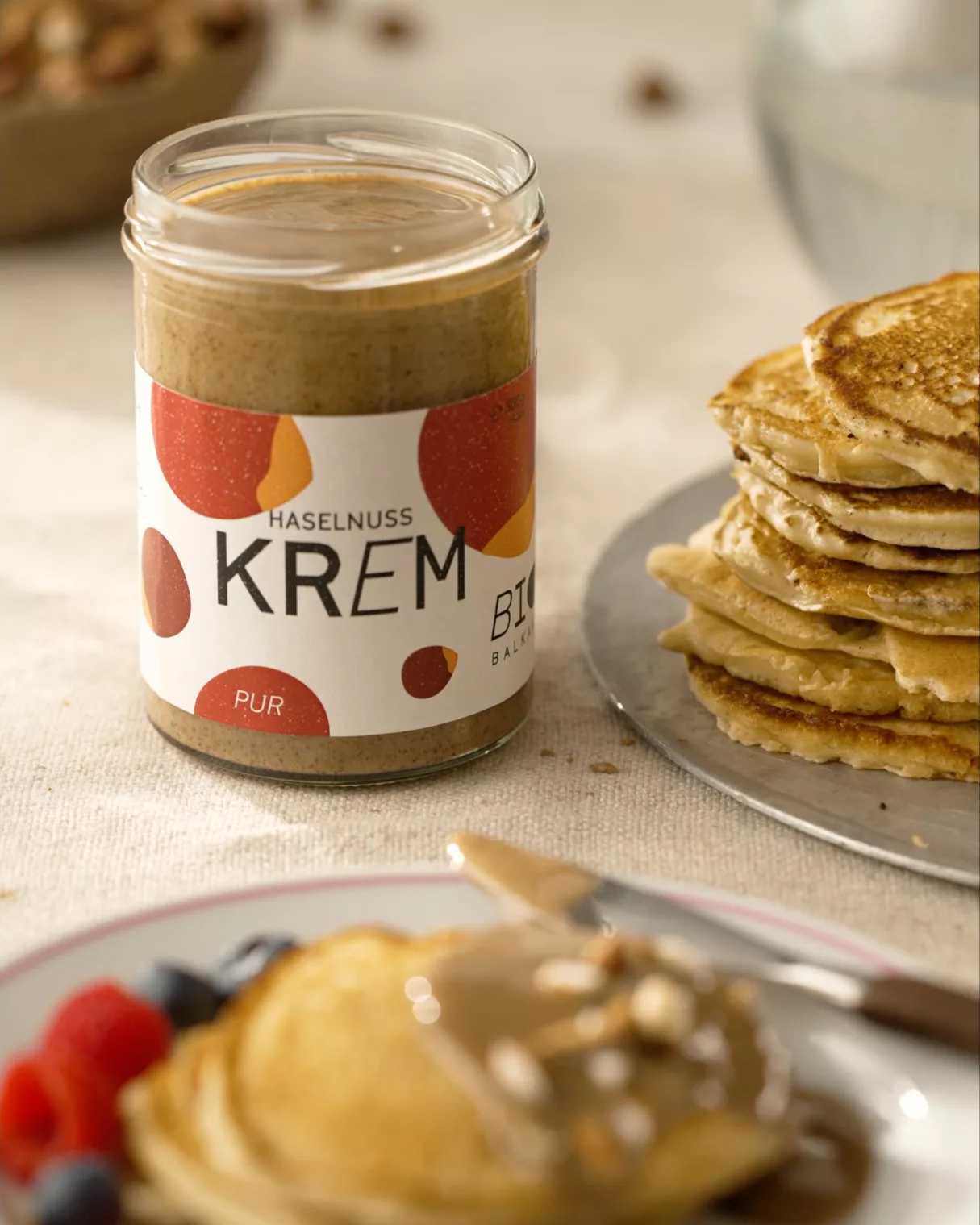 Pancakes mit einem Glas Bio Krem auf gedecktem Frühstückstisch